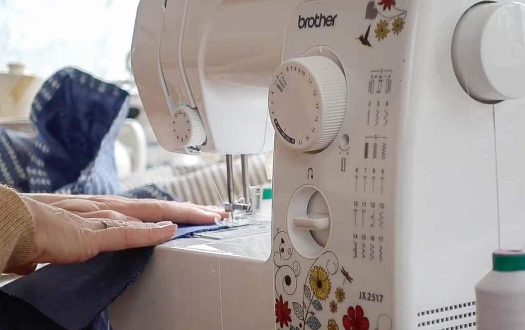 women guiding fabric through a sewing machine to create a seam