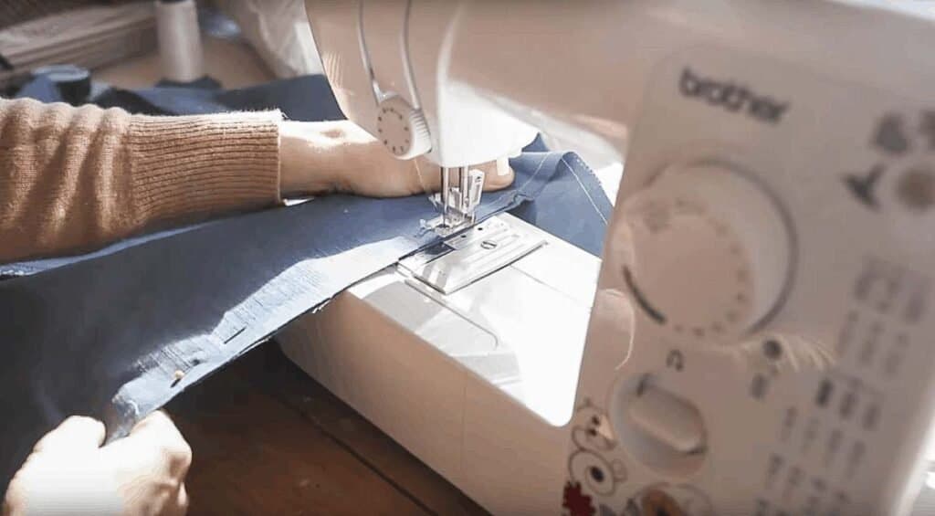 women sewing a seam on blue fabric 