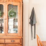 half apron hanging on a wall next to an vintage China cabinet