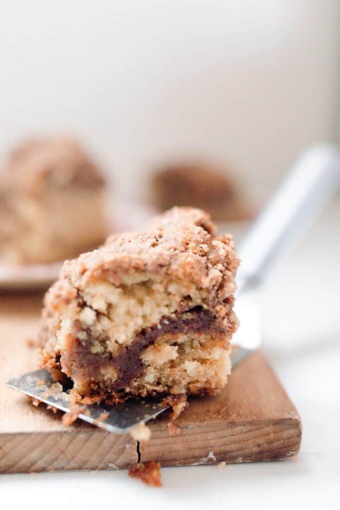 a slice of sourdough coffee cake on a spatula resting on a wood cutting board