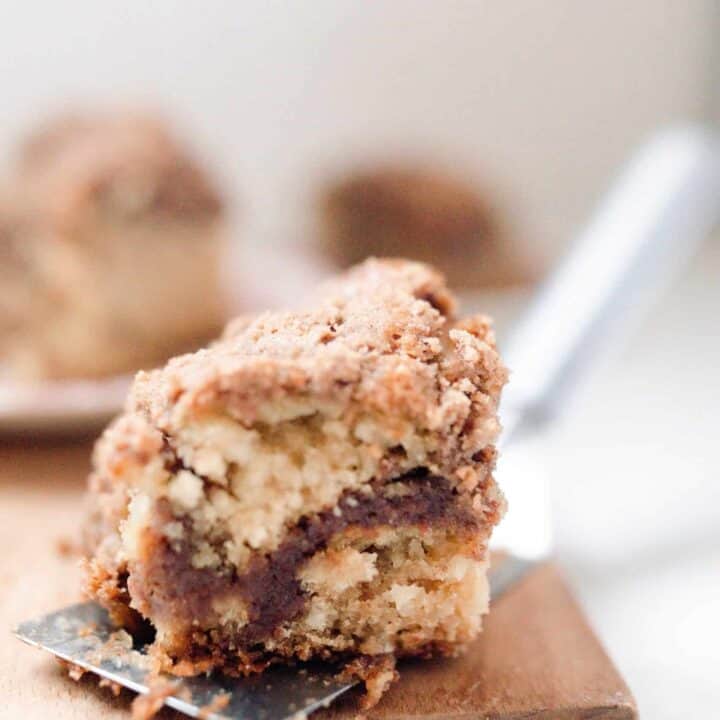 a slice of sourdough coffee cake on a spatula resting on a wood cutting board