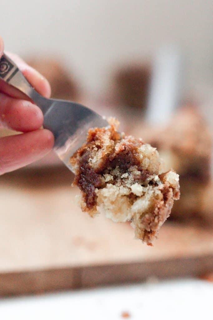 fork full of sourdough cake with a wood cutting board of in the background