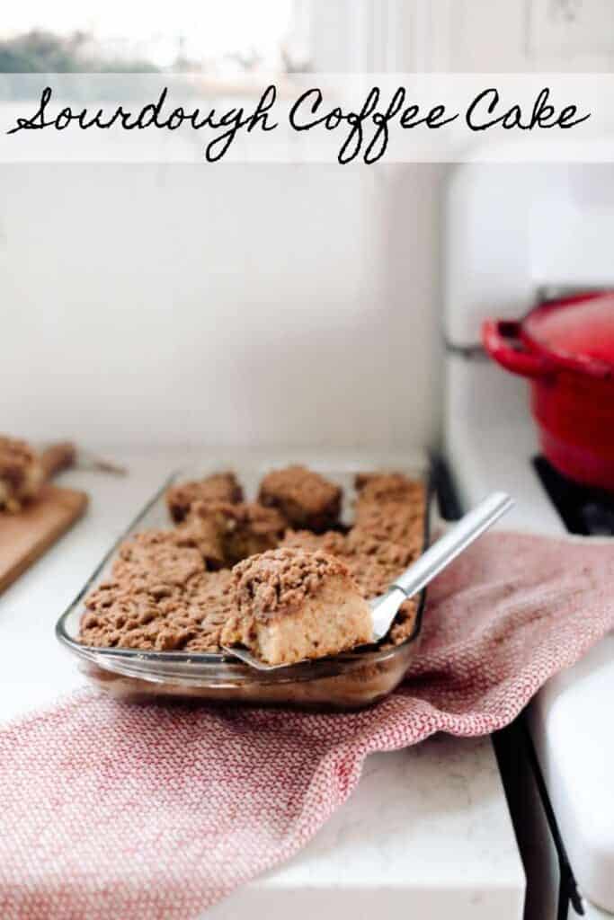 glass baking dish of sourdough coffee cake on a red and white towel on a white countertop next to an vintage stove