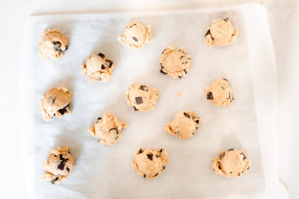 sourdough chocolate chip cookie dough balls on a parchment lined baking sheet