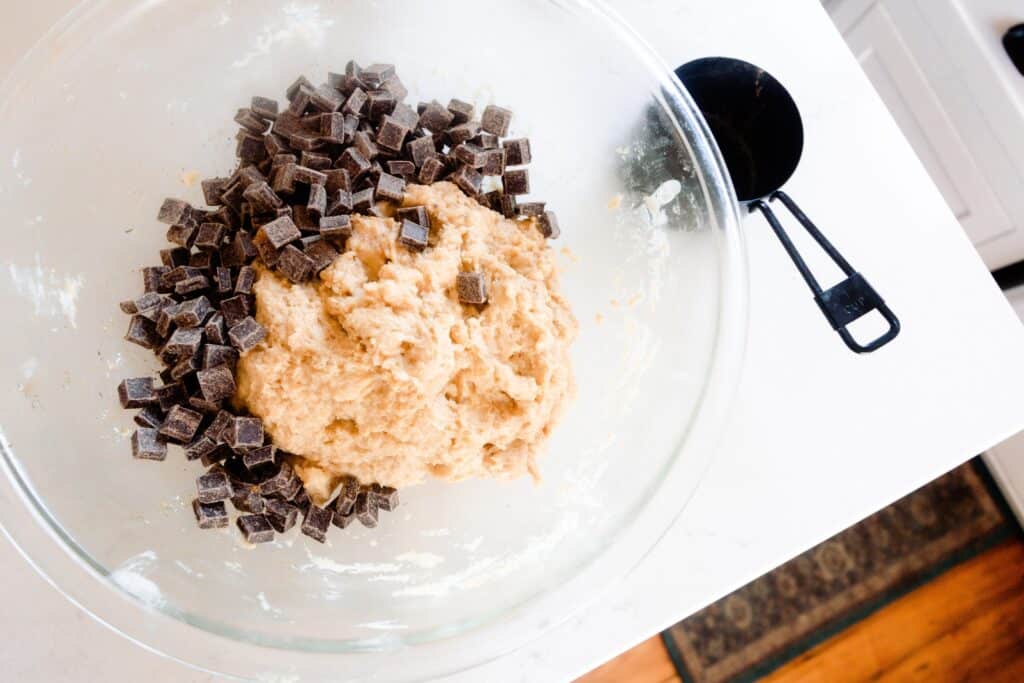 chocolate chips added to sourdough cookie dough in a glass bowl