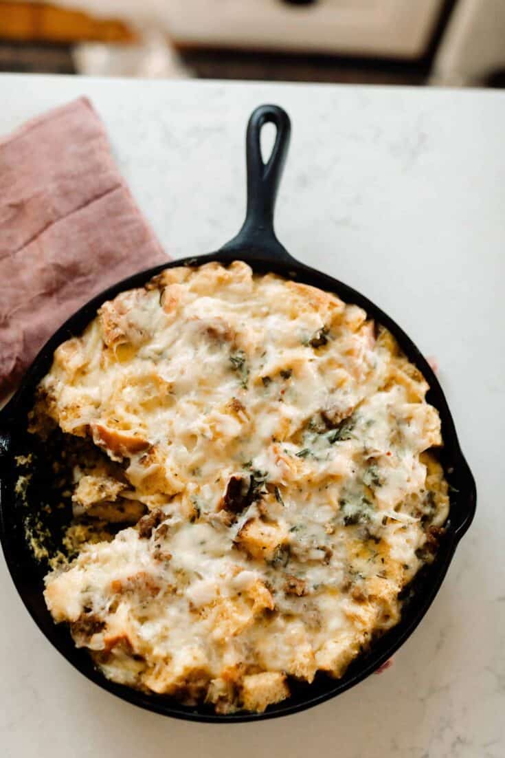 overhead photo of sourdough breakfast strata in a cast iron skillet on a red tea towel on a white quartz countertop