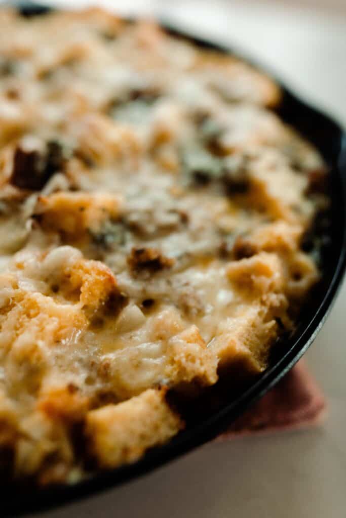 egg bake with sourdough bread in a cast iron skillet topped with cheese.