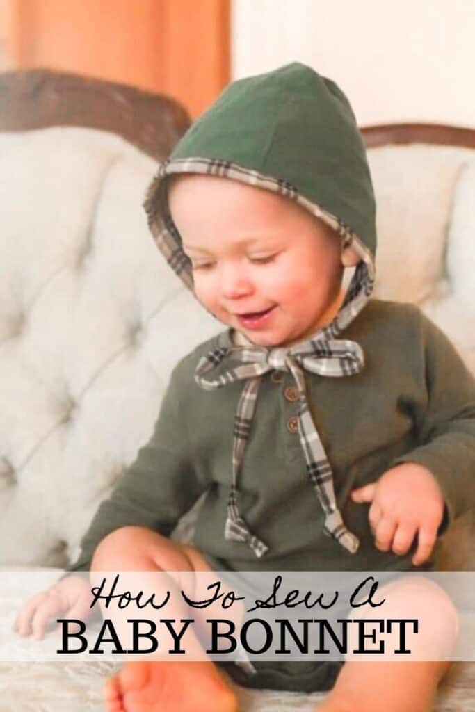 little boy smiling wearing a baby bonnet on a victorian couch