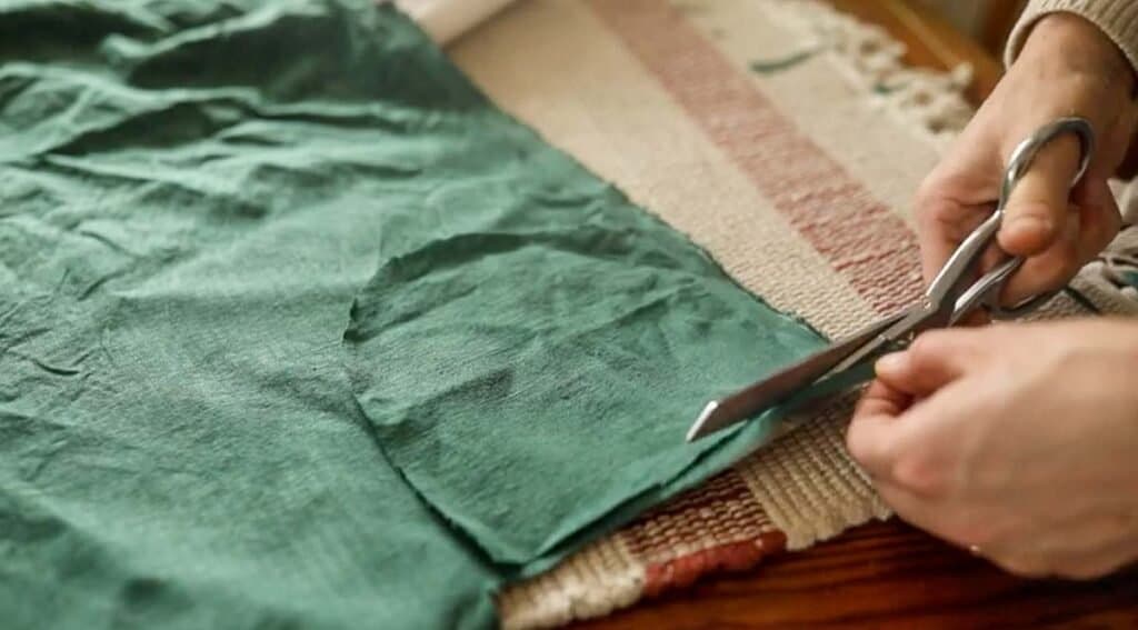 Women cutting out green fabric