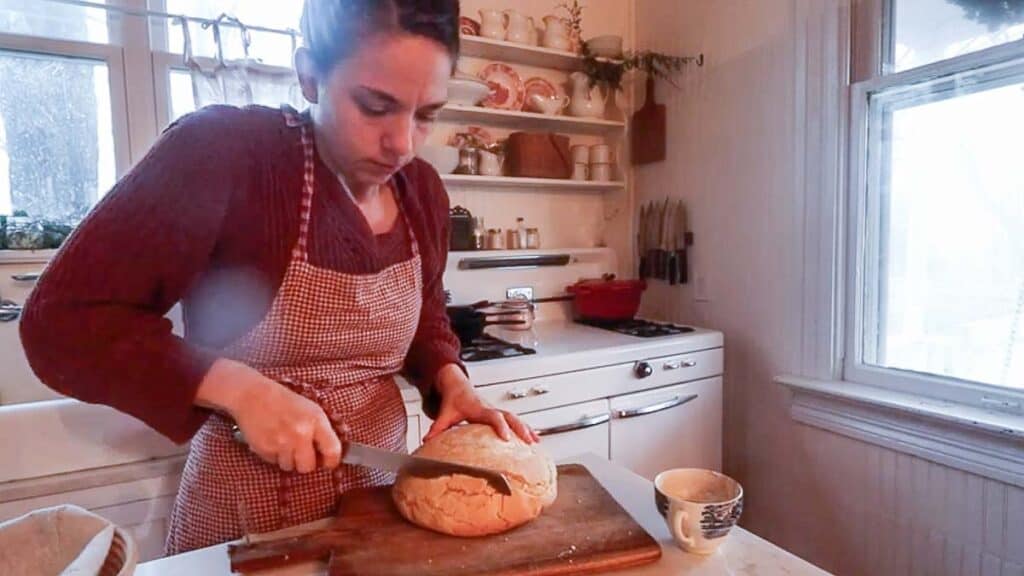 women slicing bread on a cutting board.