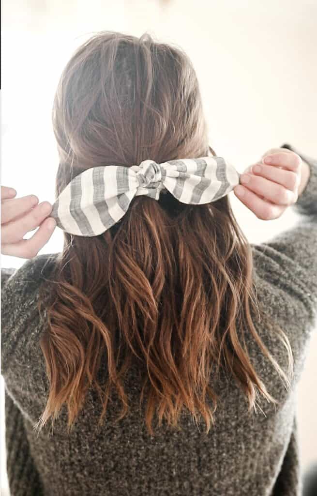 women with a gray sweater with her hair tied half up with a DIY scrunch bow