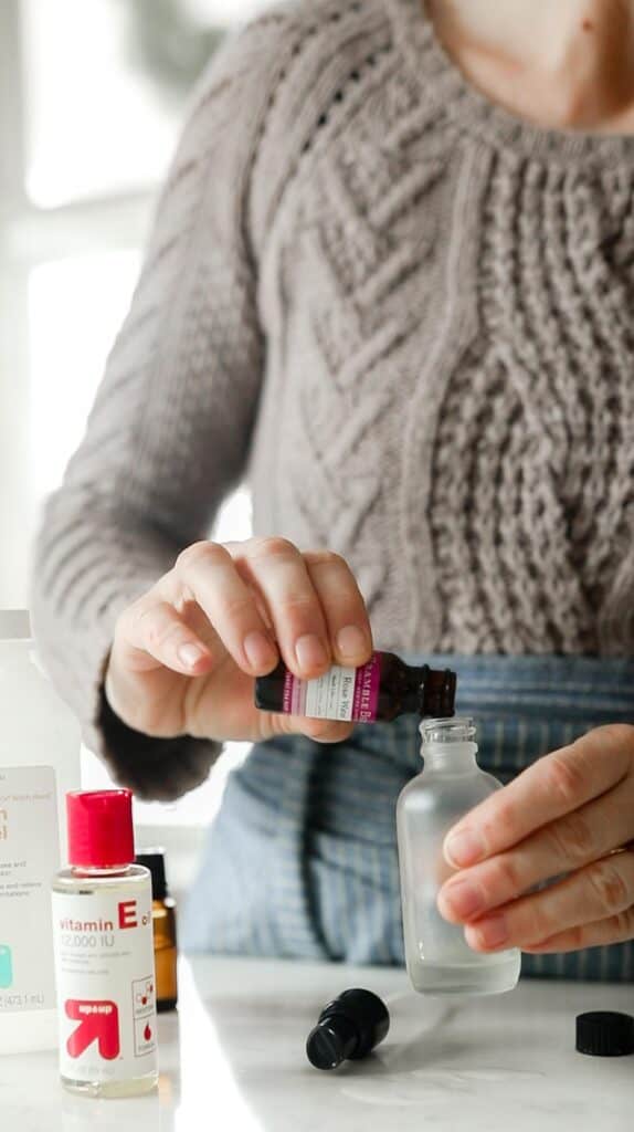 women pouring rose water into a glass bottle to make toner