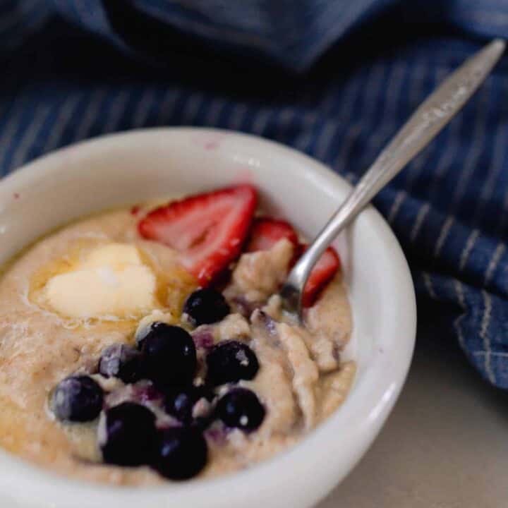 einkorn breakfast porridge in a white bowl topped with fruit