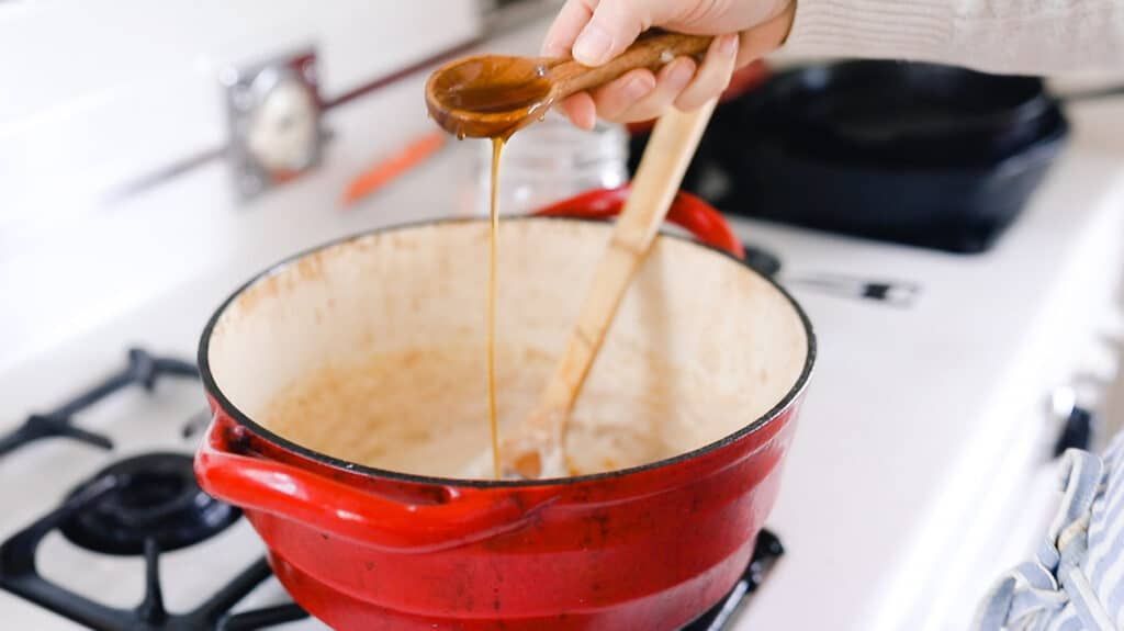 honey in a wooden spoon being poured into a large pot of cream of wheat