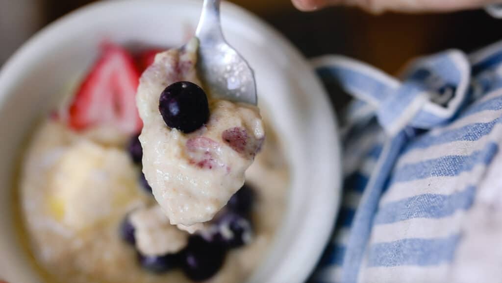 spoonful of einkorn breakfast porridge with berries in a white bowl