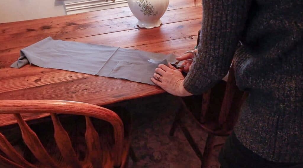 women cutting out flannel fabric to make a ruffle on a kitchen table