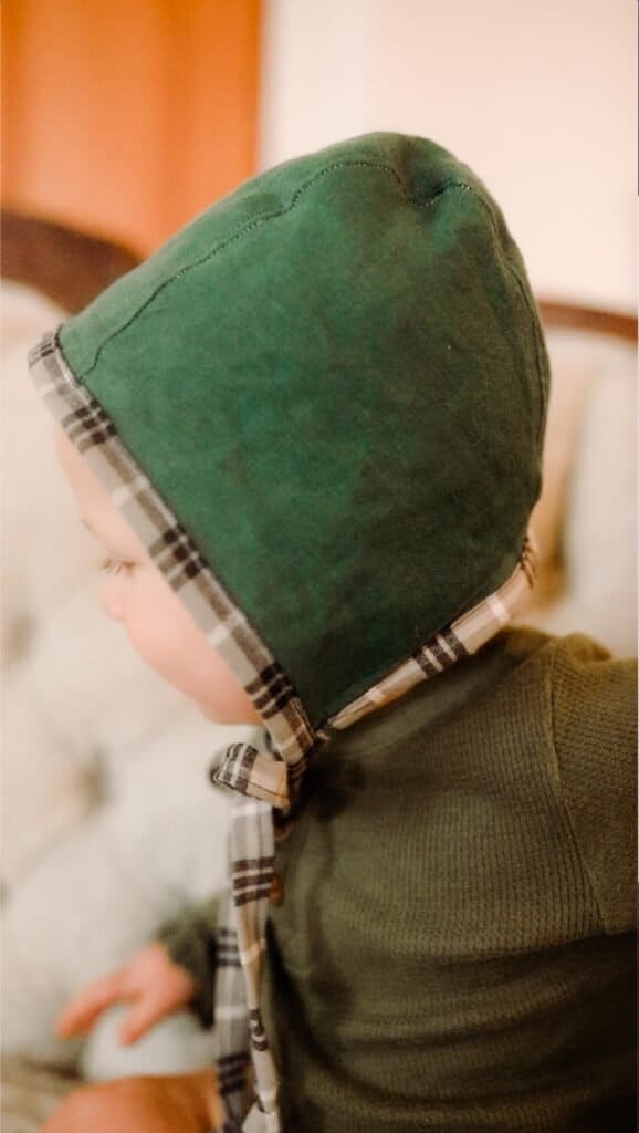 boy wearing a green homemade baby bonnet