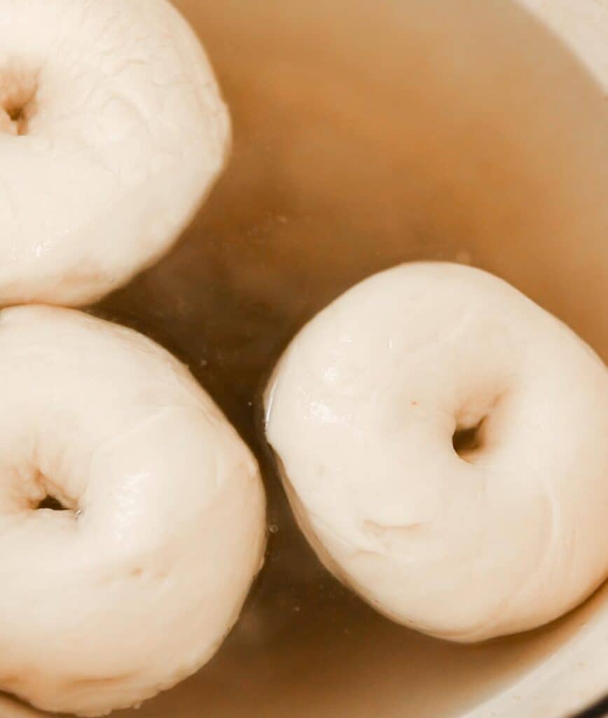 bagels being cooked in a pot of water, baking soda, and sugar
