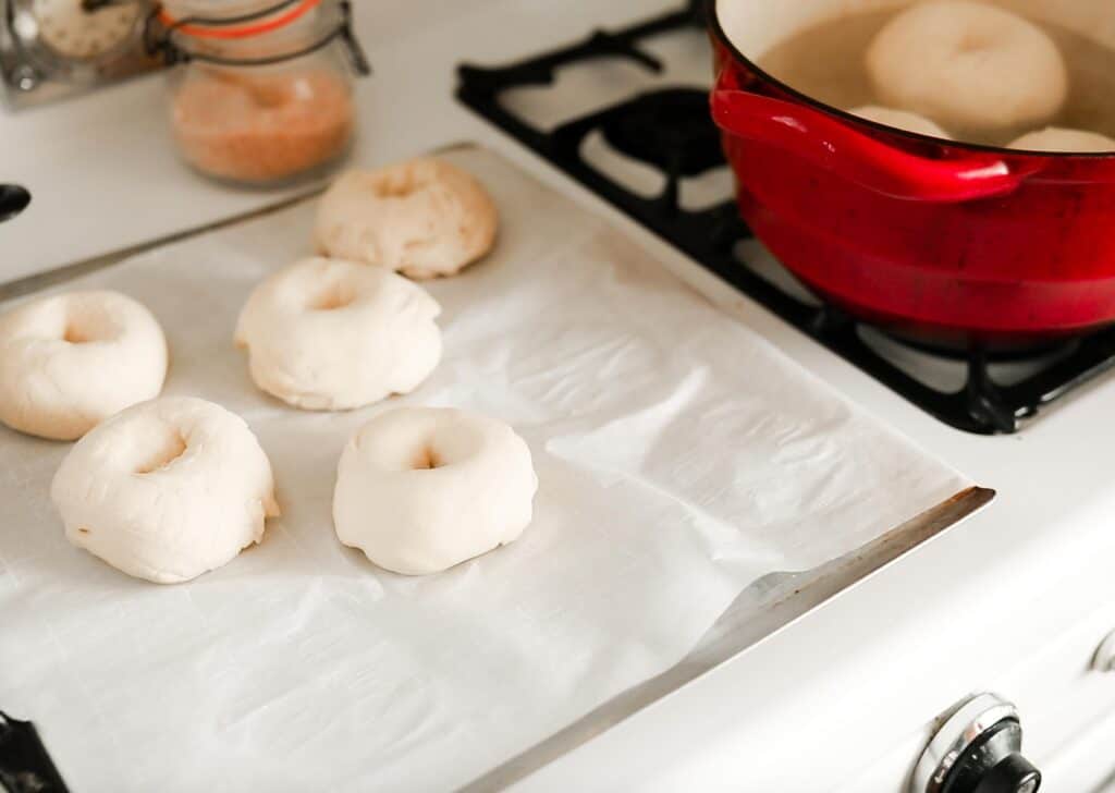 bagels being placed onto a baking sheet 