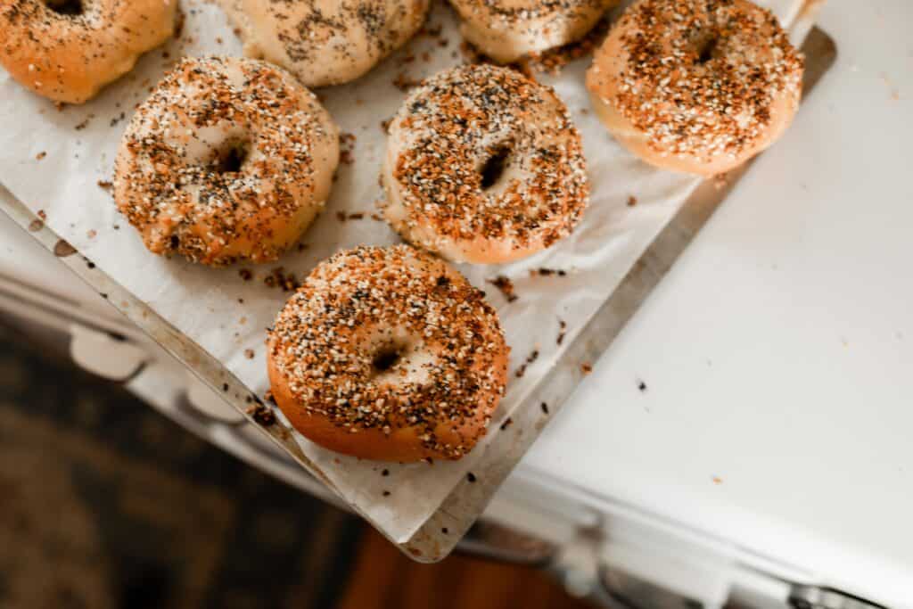 sourdough bagels baked on a stainless baking sheet on top a antique oven