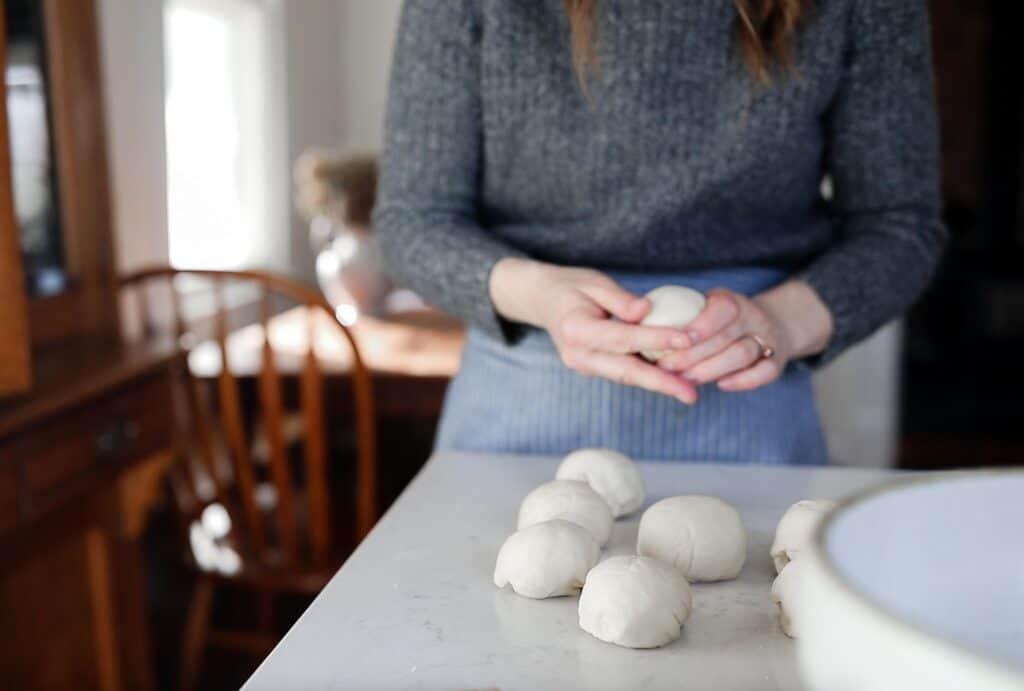 women shaping sourdough bagels on a white countertop