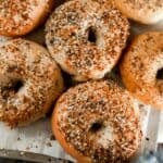 sourdough bagels with everything seasoning on a parchment lined baking sheet