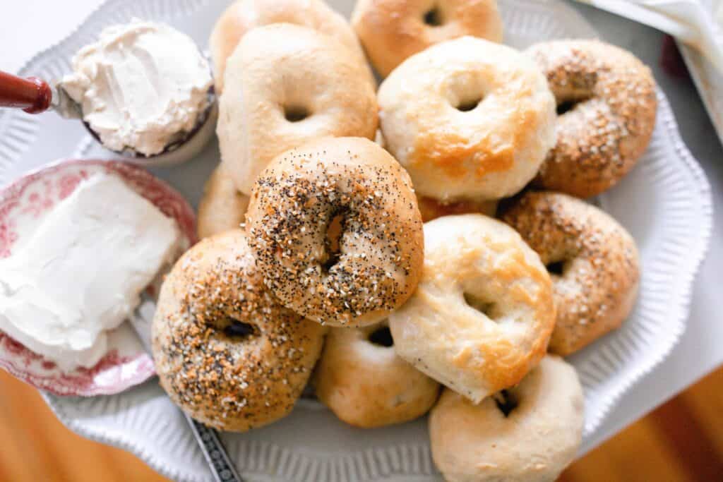 sourdough bagels on a white platter with a cream cheese on a plate