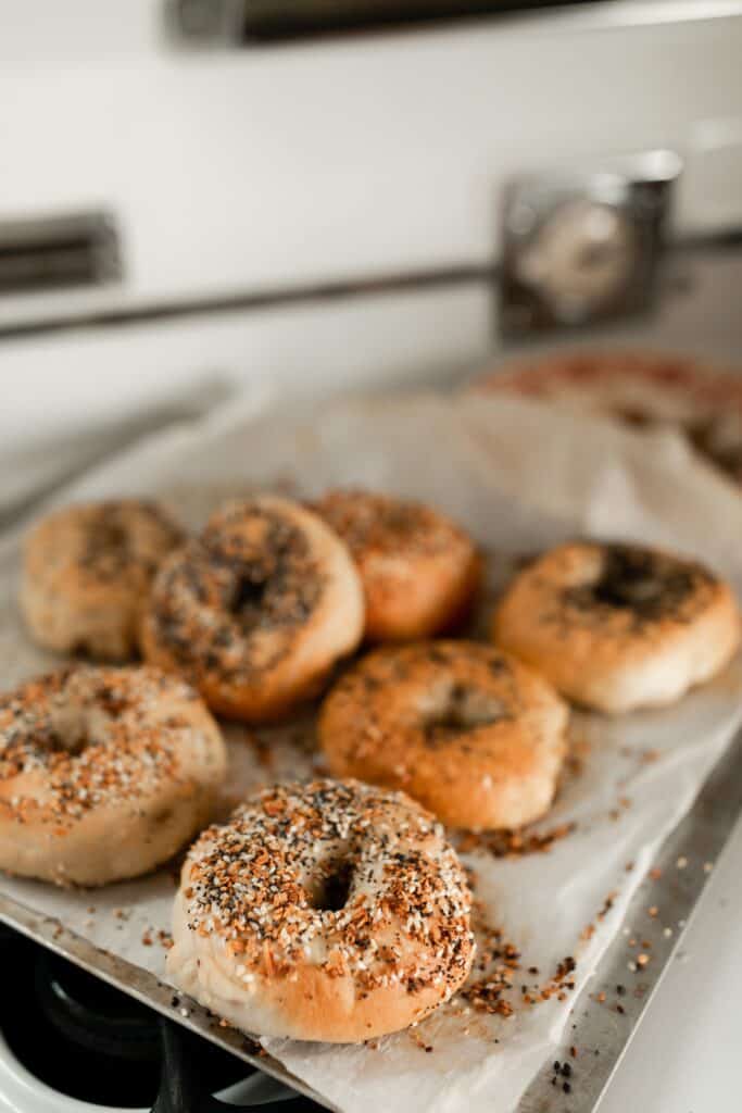 sourdough bagels on a parchment lined baking sheet on a vintage oven