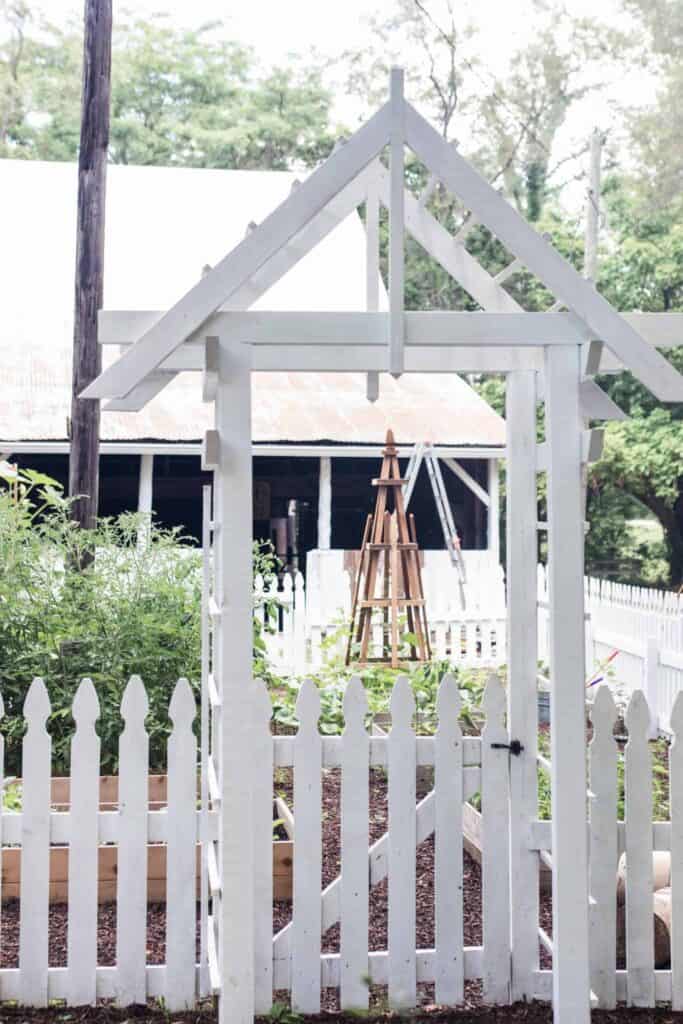 garden entrance with an arbor and a white picket fence - how to start a garden