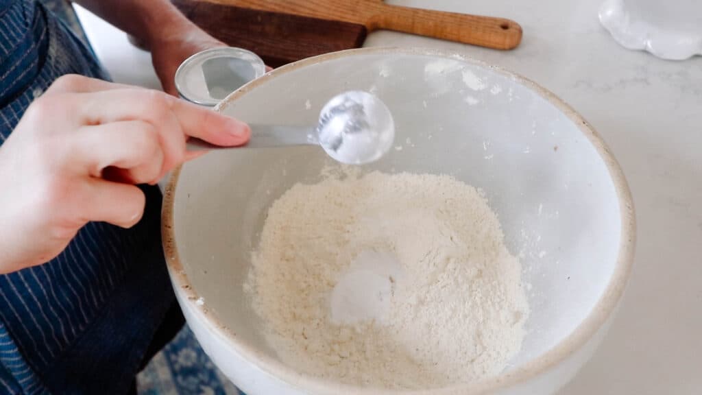 adding baking powder to a bowl of flour