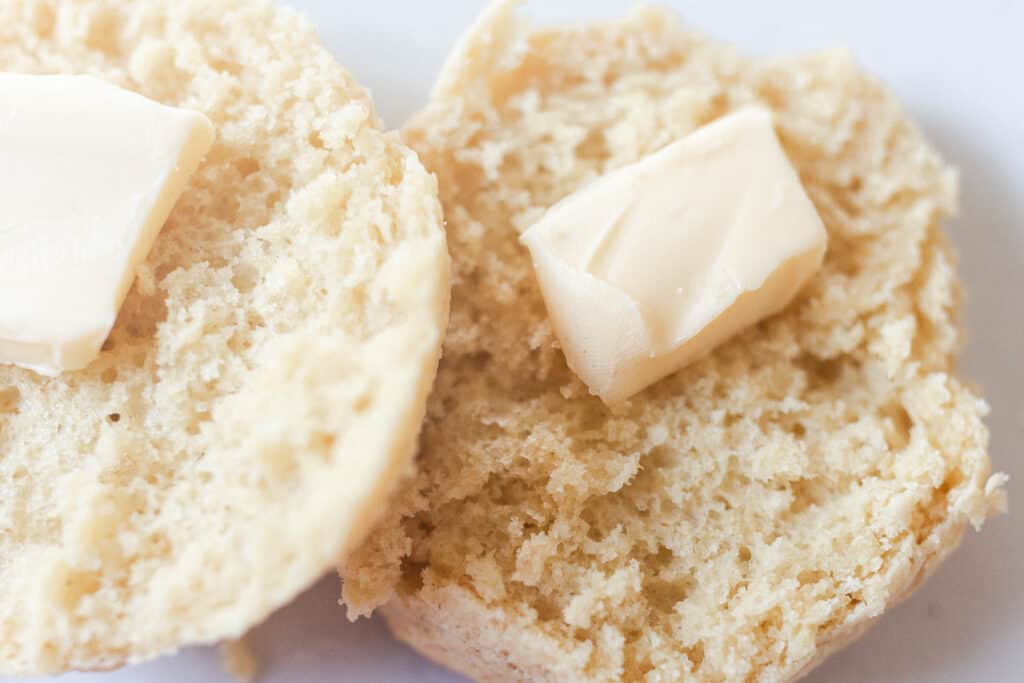 einkorn biscuits cut in half with a pat of butter on a white countertop