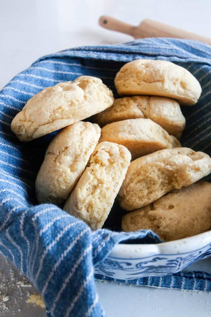 einkorn biscuits in a bowl lined with a blue and white stripped towel and a rolling pin in the background