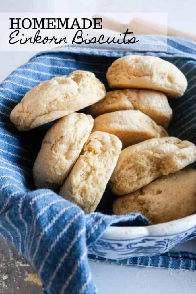 einkorn biscuits in a bowl lined with a blue and white stripped towel and a rolling pin in the background