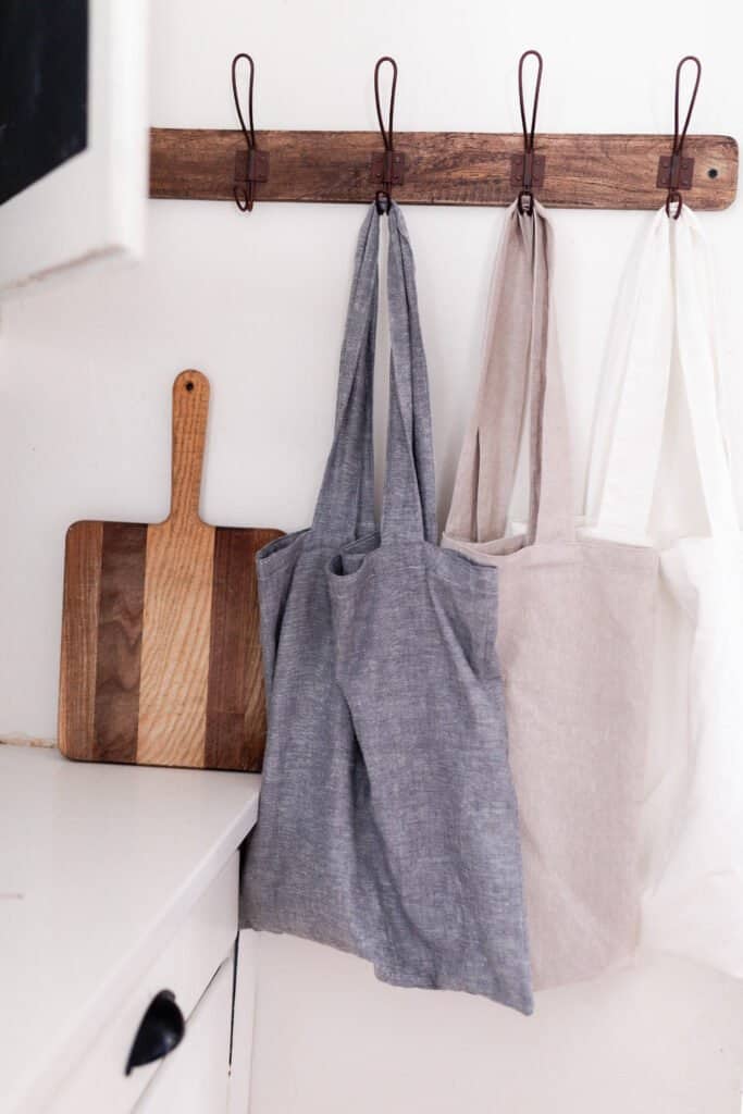 three linen bags hanging on a hook rag in a kitchen