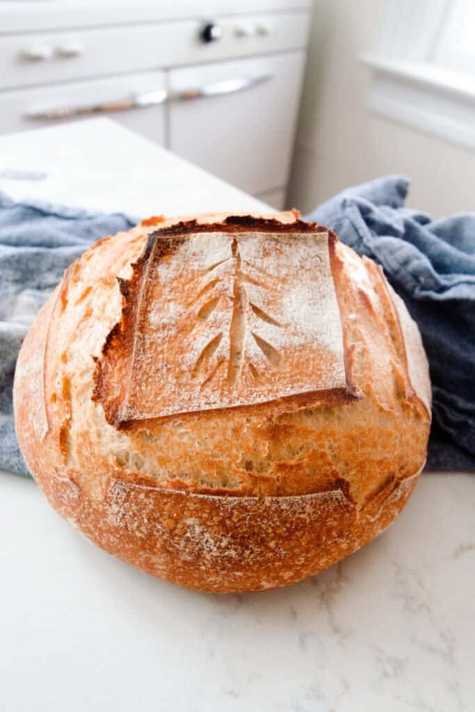 loaf of bread on a blue towel on a white quarts countertop with a vintage stove in the background