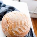 sourdough bread on a dark blue towel on a white countertop in a white kitchen