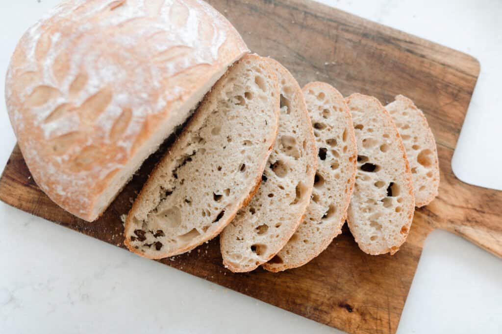 a loaf of sourdough bread sliced on a vintage wood cutting board