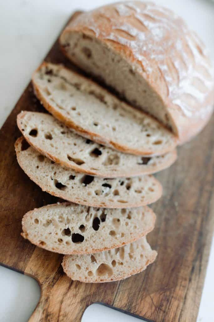 no knead sourdough bread sliced on a wood cutting board