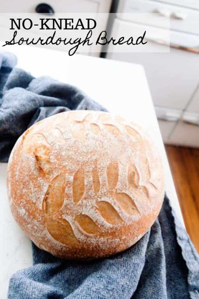 sourdough bread on a dark blue towel on a white countertop in a white kitchen