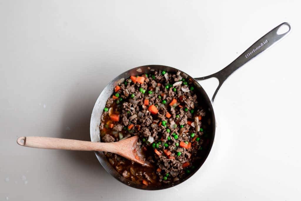 shepherd pie filling in a saucepan with a wooden spoon