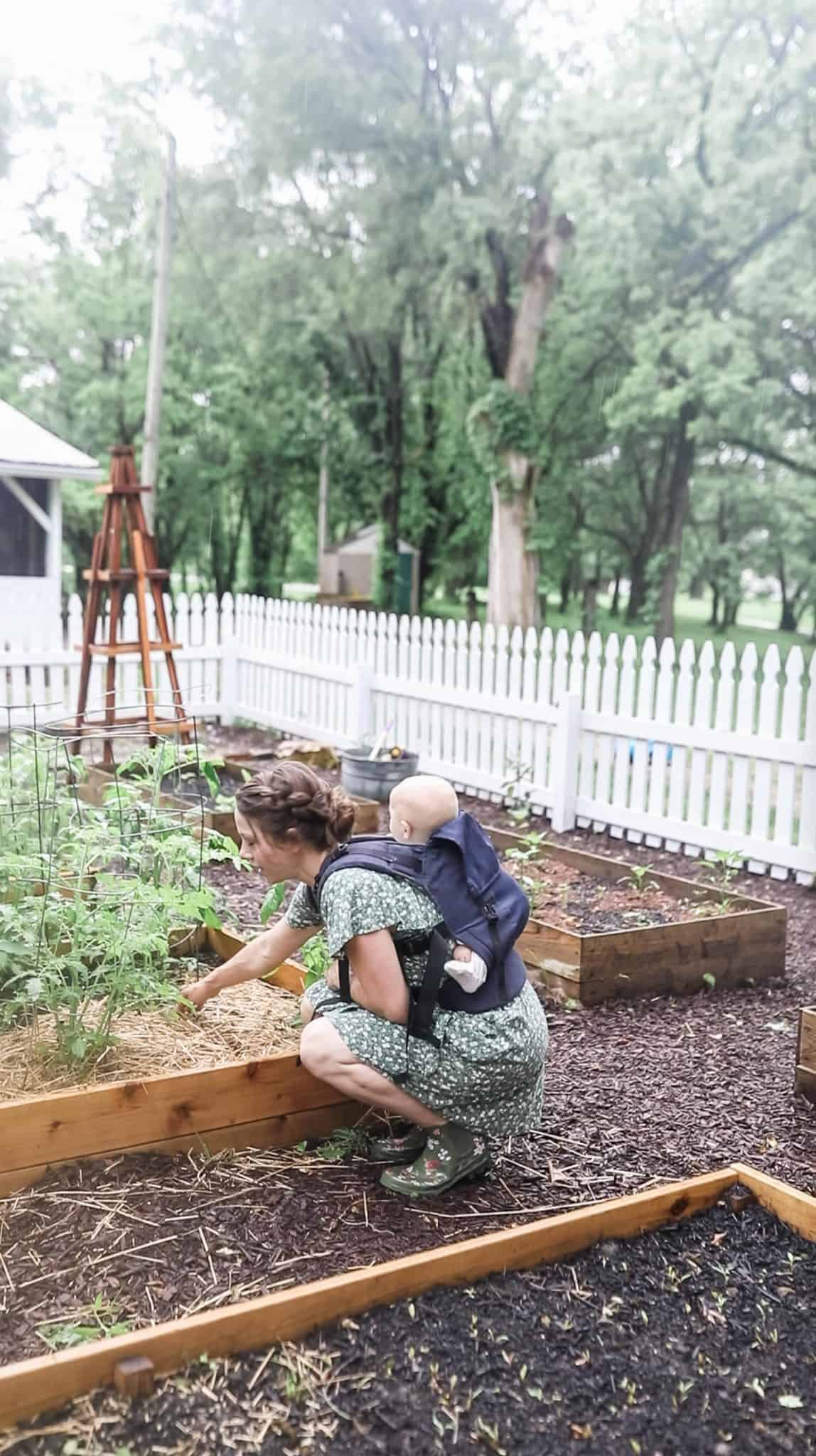 women with a baby on her back checking her garden