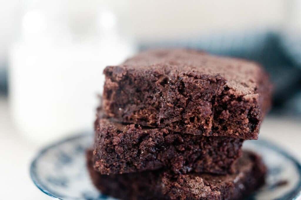 einkorn brownies on a white and blue antique plate with a jar of milk in the background