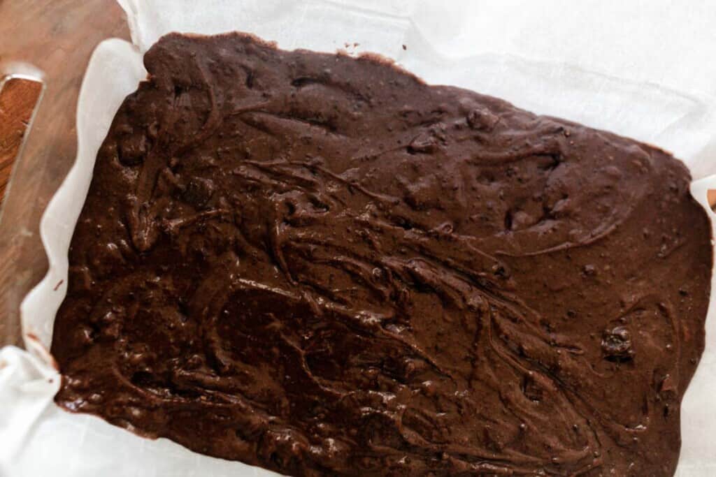 einkorn brownie batter poured into a parchment lined baking dish