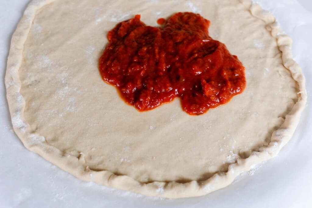 adding pizza sauce onto einkorn pizza crust