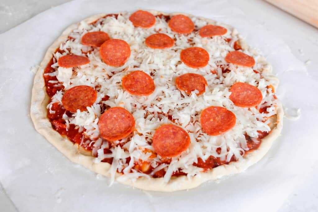 homemade pizza with cheese and pepperoni on einkorn pizza crust ready to go into the oven