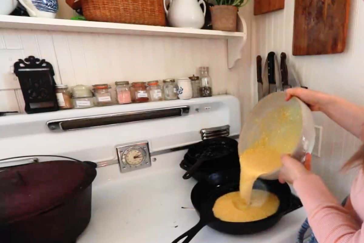 Pouring the puff pancake batter into the prepared cast iron skillet.