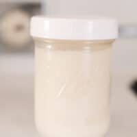 rendered beef fat in a mason jar with a white plastic lid on a white antique stove