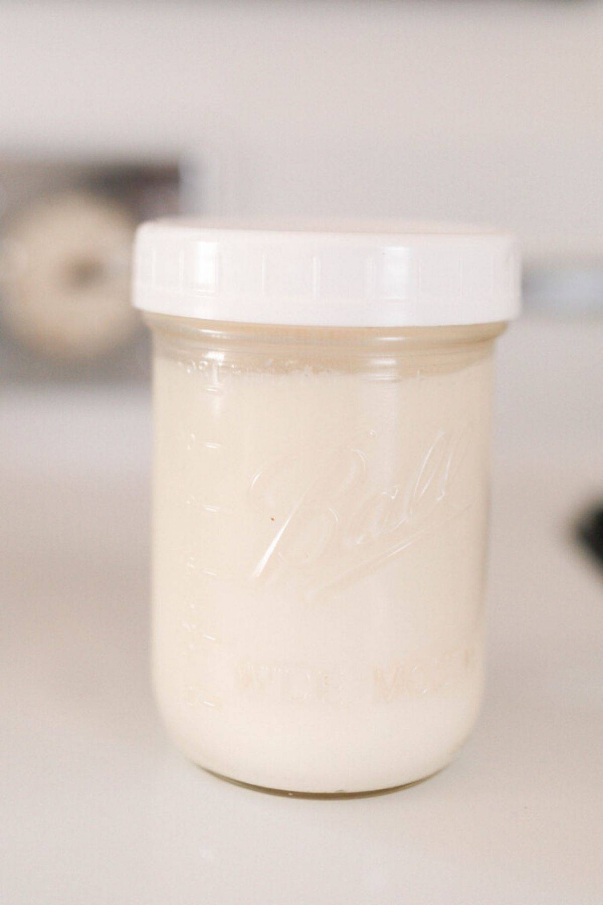 rendered beef fat in a mason jar with a white plastic lid on a white antique stove