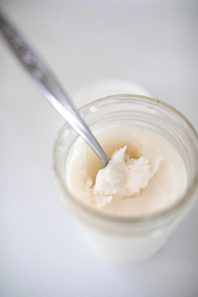 overhead photo of tallow in a mason jar with an antique spoon in the jar.