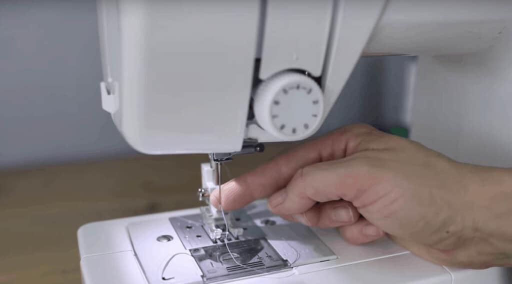 putting thread through the needle of a sewing machine.